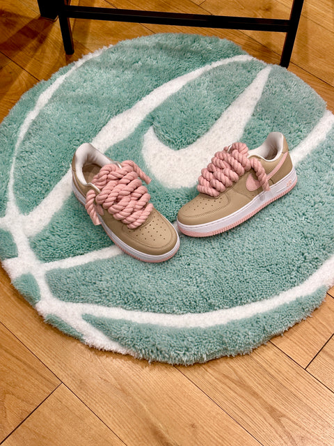 Pair of beige and pink Air Force 1 customs with rope lace displayed on a Tiffany Blue basketball rug