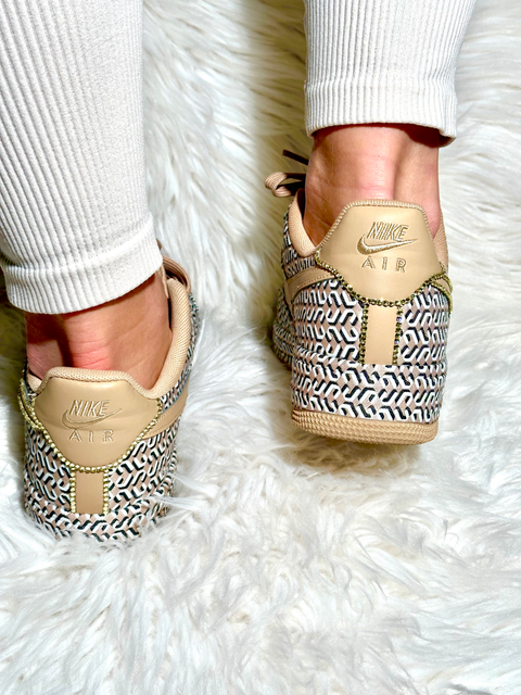 Close-up of the heel on custom Nike Air Force 1 shoes showing intricate gold crystal work and designer print.