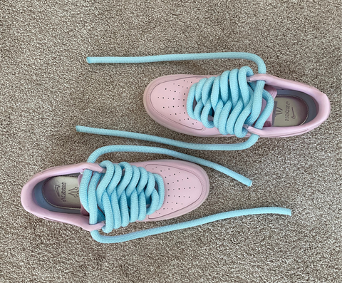 Overhead view of soft pink custom Nike Nocta AF1 sneakers highlighting the texture of the light blue waterproof rope laces.