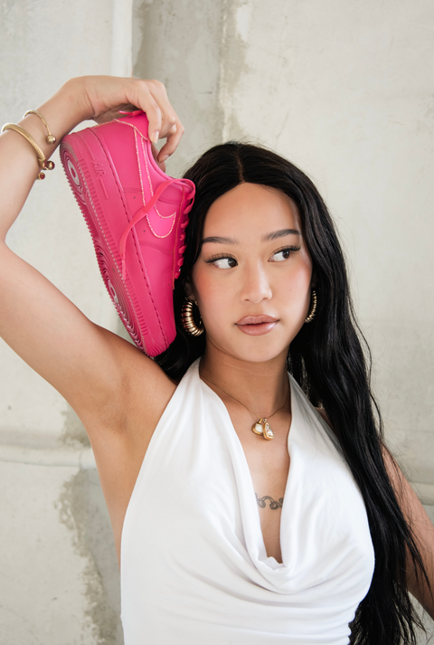 Model posing with a single fuchsia custom Nike Air Force 1 to showcase the vibrant pink color and crystal shimmer.