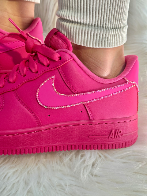 Close-up side profile of a fuchsia Nike Air Force 1 highlighting the hand-placed Swarovski crystals on the pink swoosh