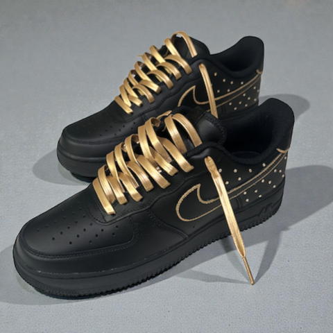 Front-facing view of custom Black Nike Air Force 1 featuring luxury gold faux leather laces and metallic gold swoosh outline.