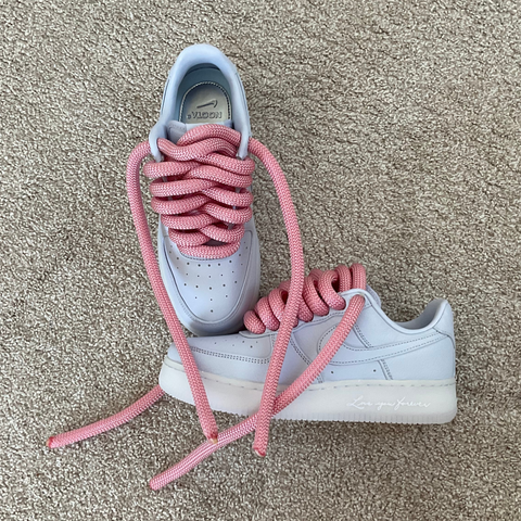 A pair of custom sky blue Nike Nocta Air Force 1s showcasing the contrast of the pink 2.0 waterproof laces and gum sole