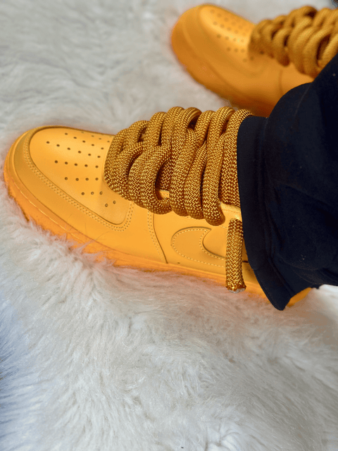 Vibrant Golden Yellow Nike Air Force 1 featuring the 2.0 rope lace system on a plush white rug