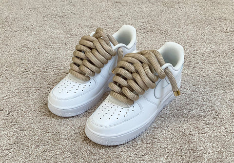 Front-side view of classic white Nike Air Force 1 sneakers upgraded with bold 2.0 gold waterproof rope laces.